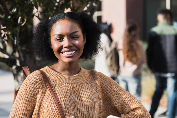 Standing on campus, the confident female college students smiles for the camera.